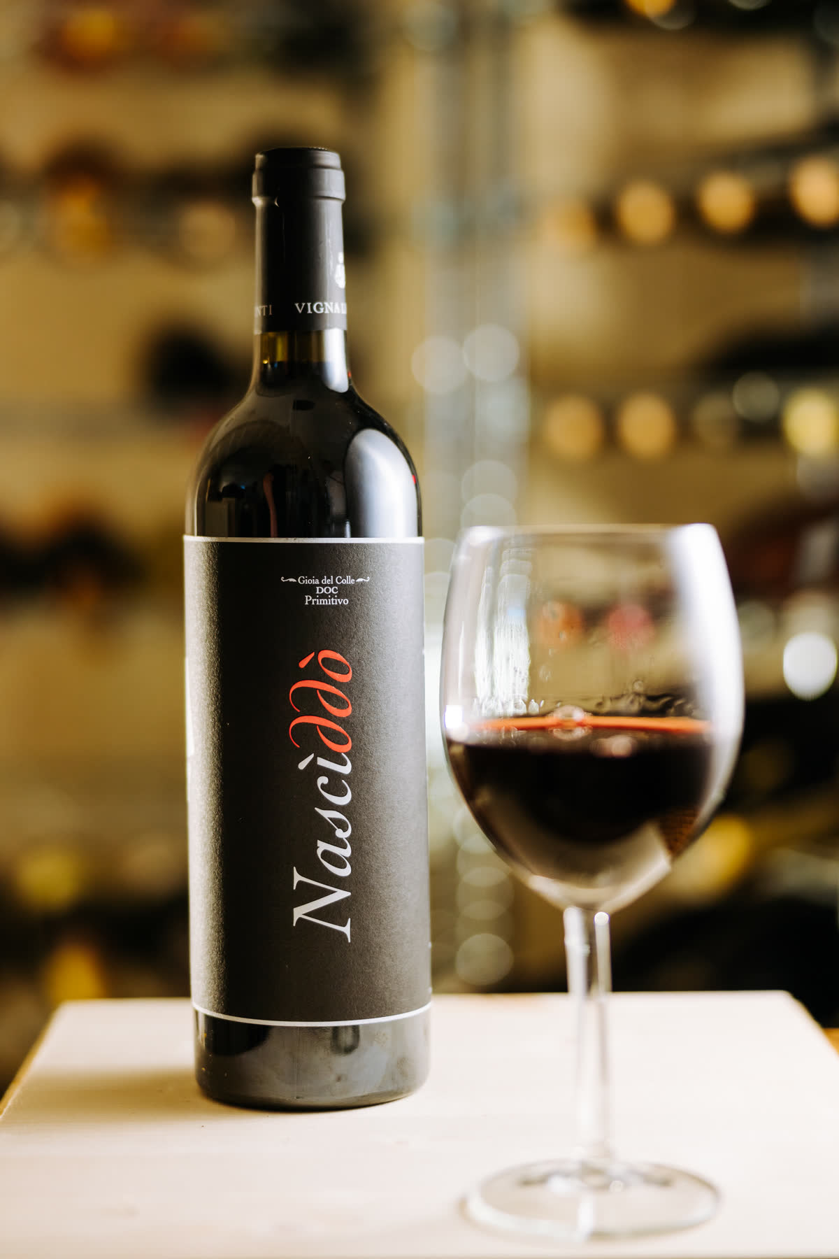 Una bottiglia di Nascìddò con un calice di vino